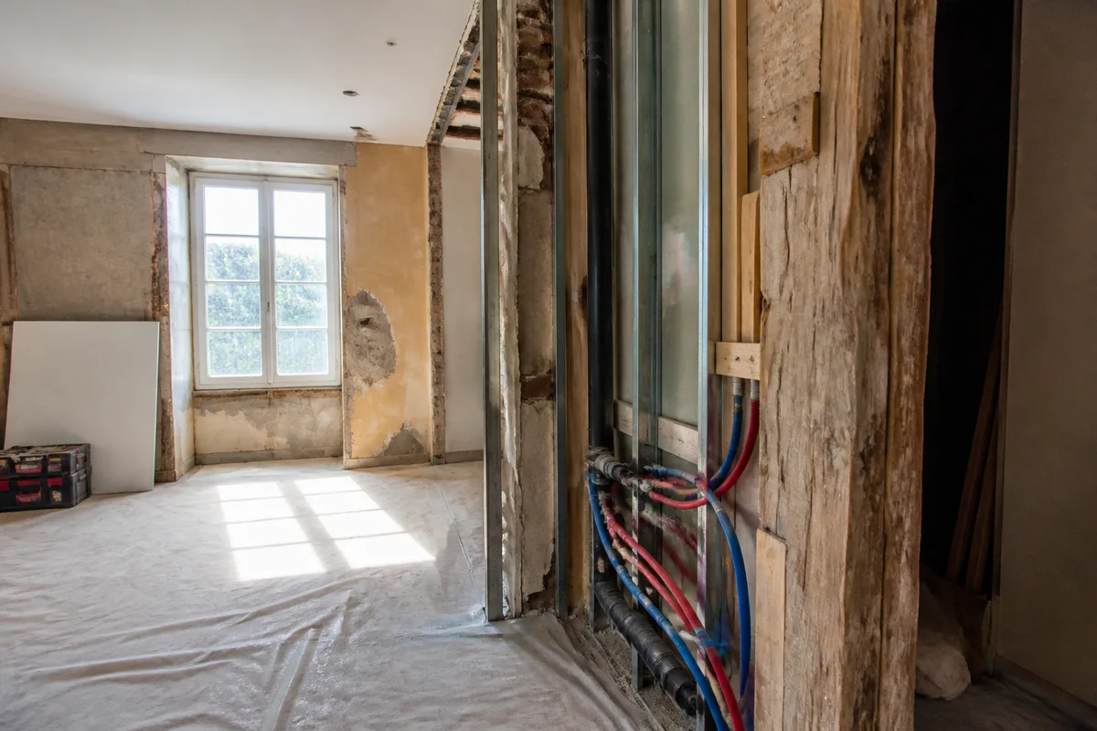 Intérieur d’une maison en rénovation avec murs ouverts et réseaux techniques visibles